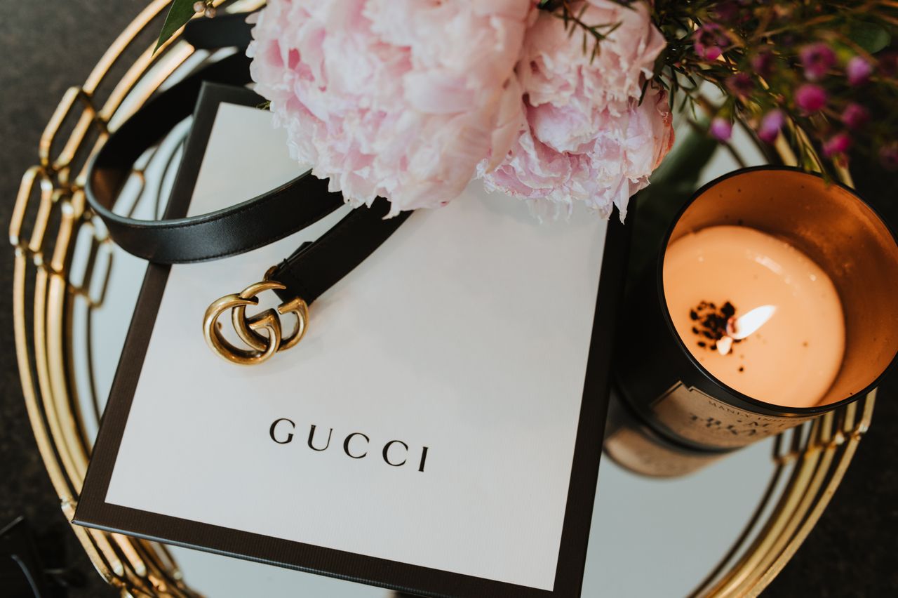 heros-img Stylish Gucci belt with candle and floral accents, showcasing luxury fashion aesthetics.