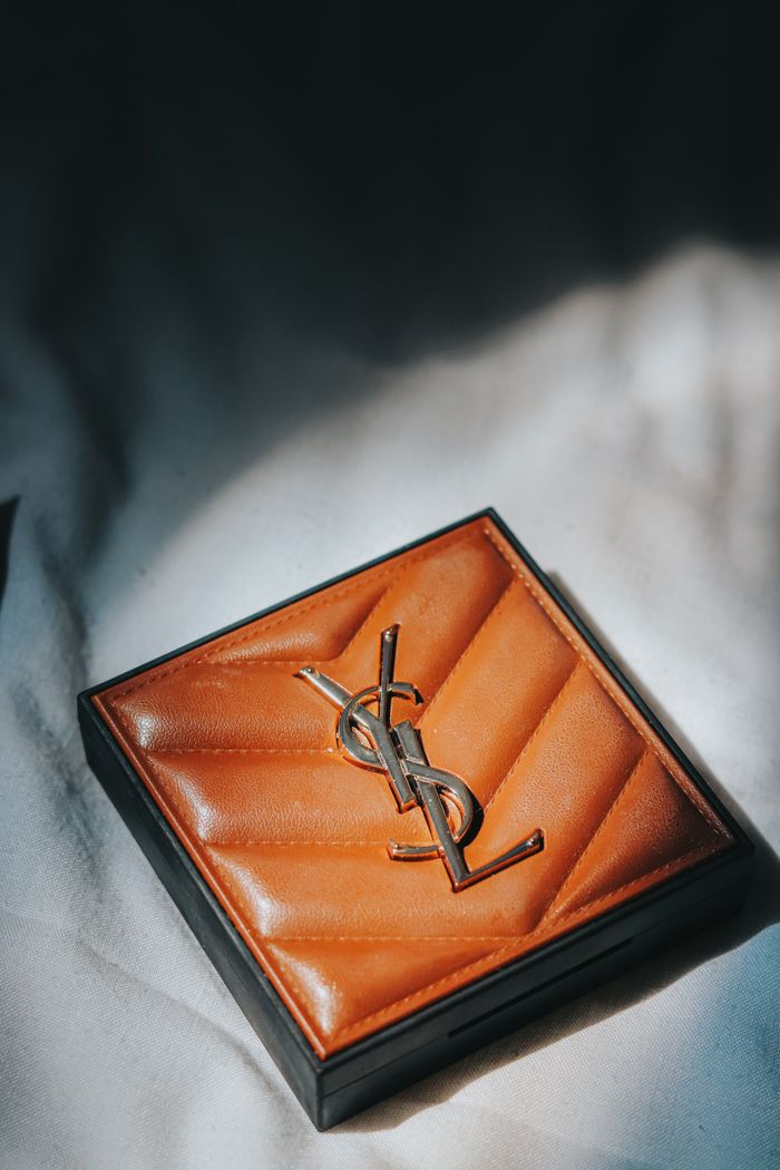 about-us-02 Luxurious brown leather wallet with elegant logo on soft white fabric, suggesting elegance and style.